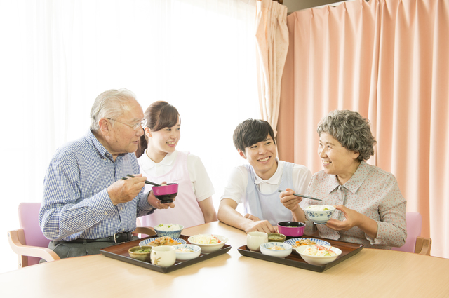 食事をする高齢者と老人ホームのスタッフ